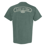 A green Tigers Jaw Comfort Colors short-sleeve tee shown from the back, featuring "Lost on You" in a decorative cream font within a curved border near the upper back—an exclusive design not found elsewhere.
