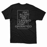 A black Sweet Pill Comfort Colors T-shirt with “I’M ALIVE AND I’M TAKING THAT FOR GRANTED” boldly printed on the back in a rectangular outline.