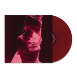 A maroon limited edition Arankai vinyl record slides from its album cover, which displays a stylized person draped in sheer fabric, their face and upper body obscured amid a striking red and black color scheme.