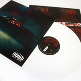 A white TX2 vinyl record slides partially out of its cover, which has dark art of a person in a car and a parental advisory label. An insert with red text appears in the background.
