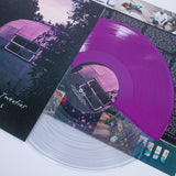 A half clear, half purple Aaron West and the Roaring Twenties vinyl rests on its sleeve with an old camper van in Monongahela Park. An insert about Roman Candles with images and text peeks out from beneath the record.