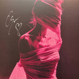 A person wrapped in pink fabric, face covered and shoulders exposed, appears against a dark background. The left side of this Arankai Signed FlatTrack image features a Limited Edition autograph with a heart symbol.