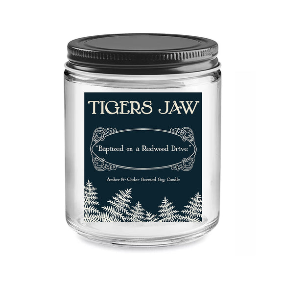 A glass jar candle with a black lid and dark label reading 