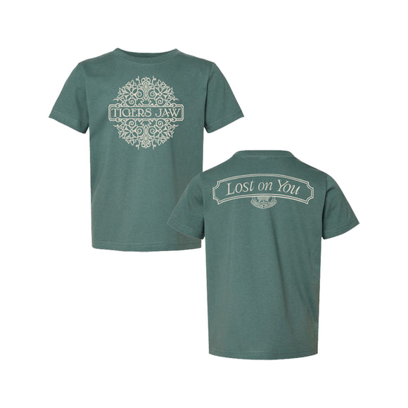 Two green toddler T-shirts by Tigers Jaw are shown. One features a unique circular floral motif with the brand’s name on the back, while the other displays 'Lost on You' in a banner above a small graphic on the back.