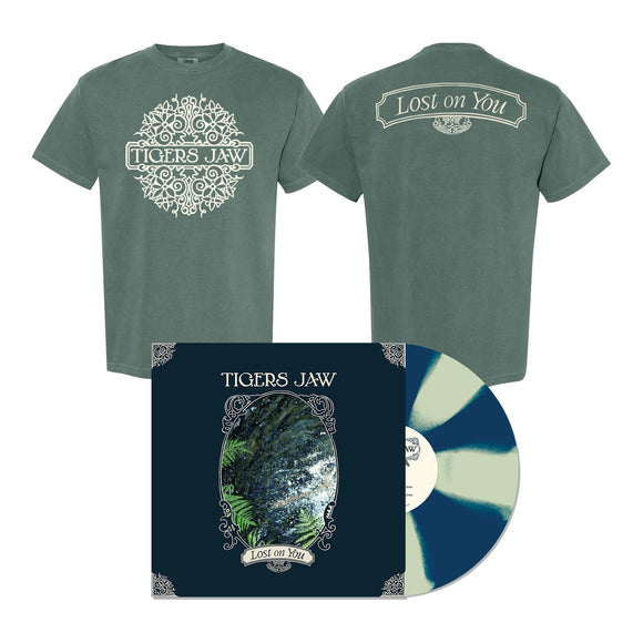 A limited edition green Tigers Jaw Comfort Colors T-shirt with ornate white designs and text, shown above a blue and cream splatter Tigers Jaw vinyl with a foliage-themed album cover.