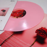 A pastel pink vinyl from With Confidence’s Love And Loathing album rests on a matching cover and insert, both featuring a red rose and the Pink Tracklist in white text, set against a light backdrop.
