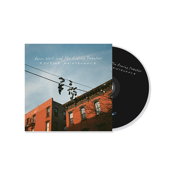 A CD partially in its case for Routine Maintenance by Aaron West and the Roaring Twenties, featuring an album cover with sneakers hanging from a powerline above brick buildings under a blue sky.